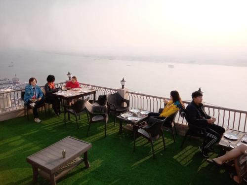 a group of people sitting at tables on a balcony at Hotel Sita Place On Heritage Ghats Of Benaras in Varanasi