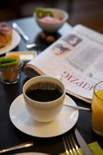 a cup of coffee on a plate on a table at Hotel Fregehaus in Leipzig