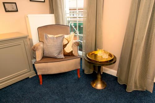 a chair with pillows sitting next to a table at Nordseehotel Kröger in Langeoog