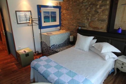 a bedroom with a bed and a stone wall at Micro-Hostal La Puerta del Perdón in Villafranca del Bierzo