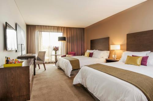 um quarto de hotel com duas camas e uma secretária em Hotel Morrison Usaquén em Bogotá