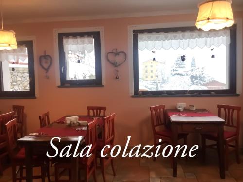 a dining room with two tables and two windows at Agriturismo B&B Chèvres à Cheval in Aosta