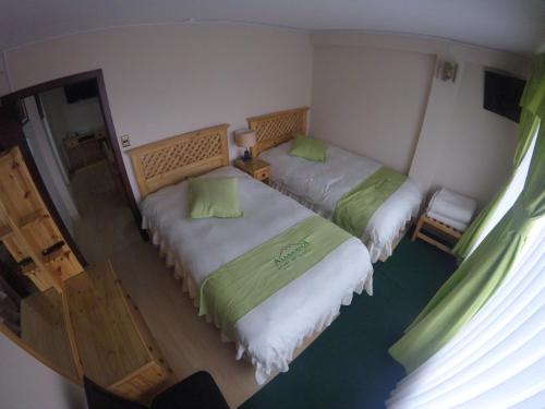 two beds in a room with green and white sheets at Almudena Apart Hotel in La Paz
