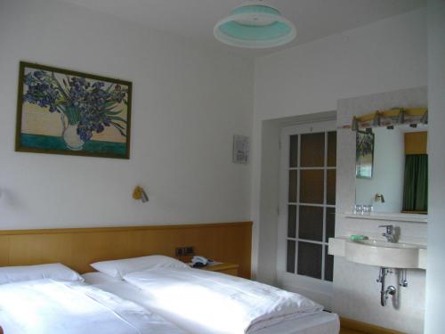 a bedroom with a bed and a sink and a mirror at Hotel Villa Emilia in Ortisei