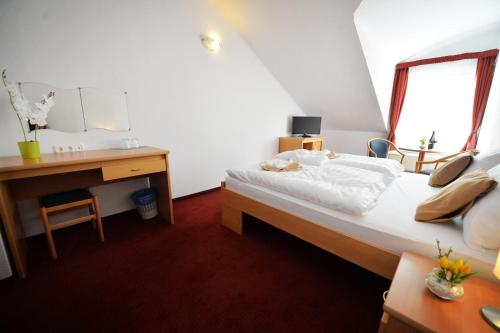 a bedroom with a bed and a desk and a window at Panorama Hotel Noszvaj in Noszvaj