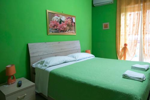 a green bedroom with a large bed and a window at Campi Flegrei House in Naples