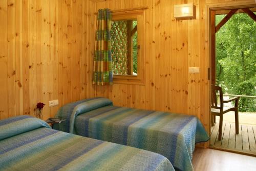 Habitación de madera con 2 camas y ventana en Camping Bassegoda Park, en Albanya