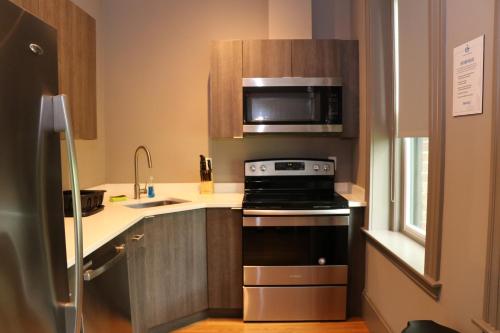 a small kitchen with a stove and a microwave at A Stylish Stay w/ a Queen Bed, Heated Floors.. #14 in Brookline
