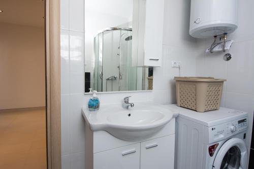biała łazienka z umywalką i pralką w obiekcie Apartments Iva w Trogirze