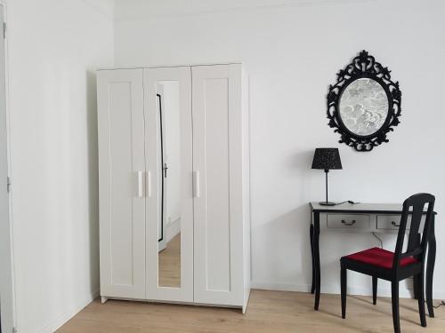 a white cabinet with a mirror next to a desk at L'Impératrice - en cœur de Bastide de Geaune in Geaune