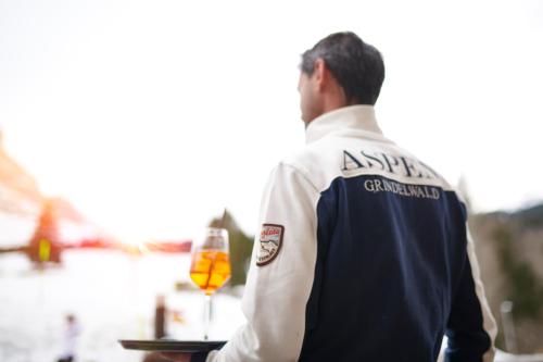 a man holding a table with a glass of wine at Aspen Alpine Lifestyle Hotel in Grindelwald