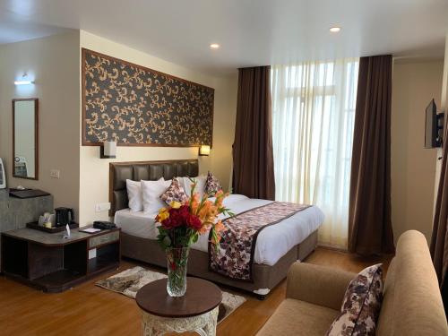 a hotel room with a bed and a vase of flowers at Voyage The Aryan Regency in Pelling