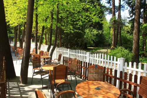 a patio with tables and chairs and a white fence at Hotel Camelot in Szczawno-Zdrój