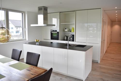 a kitchen with white cabinets and a wooden table at Zweite Heimat in Lochau