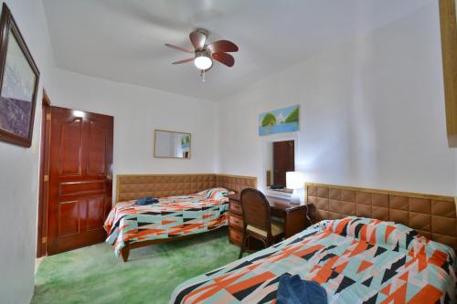 a hotel room with two beds and a ceiling fan at Villa Alégria in Santa Bárbara de Samaná