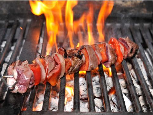 a group of meat on a grill with flames at Hotel Salobreña Suites in Salobreña
