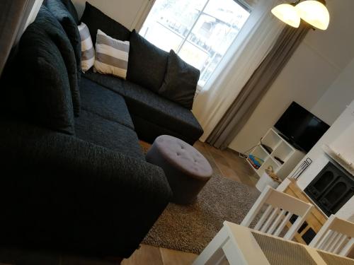 Una sala de estar con un sofá negro y una ventana. en Leviraitti 4 A2, en Kittilä