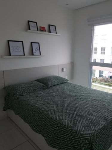 ein Schlafzimmer mit einem Bett mit einer grünen Bettdecke und einem Fenster in der Unterkunft Porto de Galinhas - Muro Alto Condomínio Clube in Porto De Galinhas