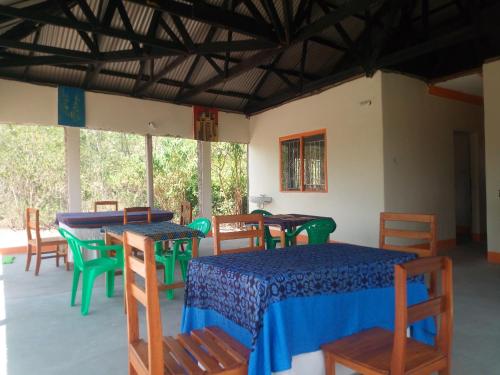 a dining room with tables and chairs and windows at The Elephant Home in Katunguru