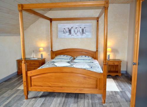a wooden canopy bed with blue pillows in a bedroom at Chambres d'Hôtes Le Nid d'Iroise in Lanildut
