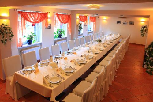 a long table with white tables and chairs in a room at Bukowy Dworek in Szczawno-Zdrój