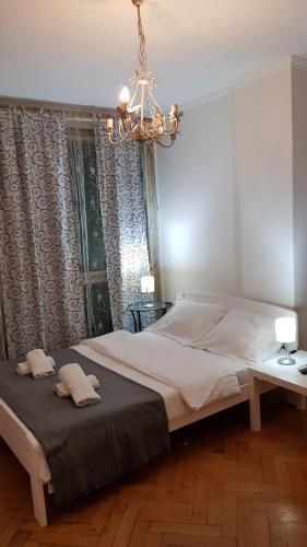 a bedroom with a large white bed and a chandelier at Apartman Panorama Glavna ulica in Užice