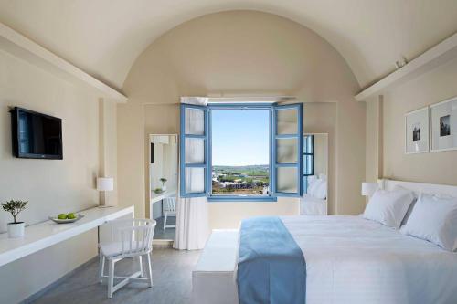 a bedroom with a large white bed and a window at Acroterra Rosa Luxury Suites & Spa in Akrotiri