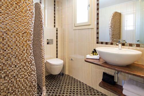 a bathroom with a sink and a toilet at Acroterra Rosa Luxury Suites & Spa in Akrotiri