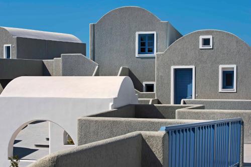 a row of gray houses with a blue door at Acroterra Rosa Luxury Suites & Spa in Akrotiri