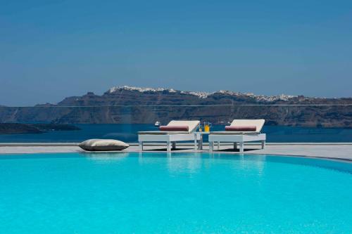 a swimming pool with two lounge chairs and a table at Acroterra Rosa Luxury Suites & Spa in Akrotiri