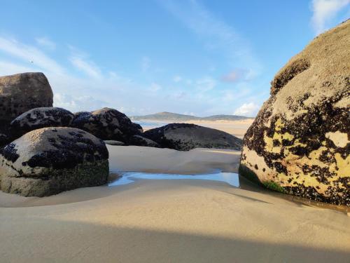 un grupo de rocas grandes en una playa de arena en Casa do patín, en Palmeira