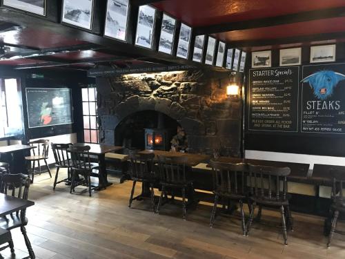 a restaurant with a stone fireplace and tables and chairs at Crown and Anchor Inn in Findhorn