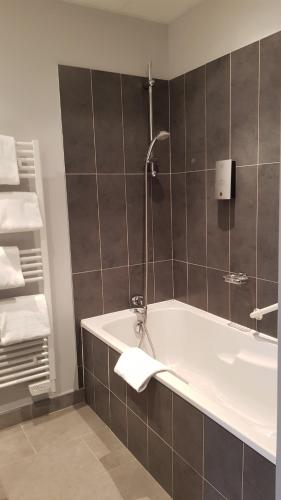a bathroom with a bath tub and a sink at Logis Hôtel des Deux Forts in Salins-les-Bains