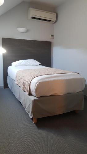 a bedroom with a large bed with a air conditioner at Logis Hôtel des Deux Forts in Salins-les-Bains