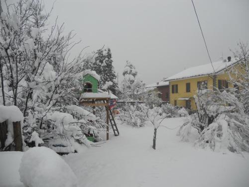 a yard covered in snow with a house in the background at B&B Pervinca in Rocca Grimalda
