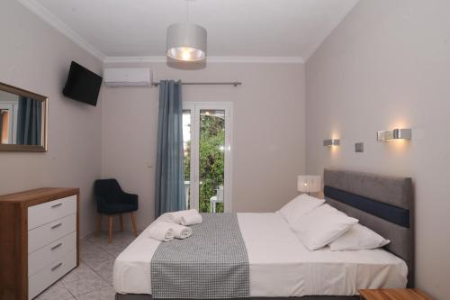 a bedroom with a bed and a chair and a window at Kalimera Apartments in Kassiopi