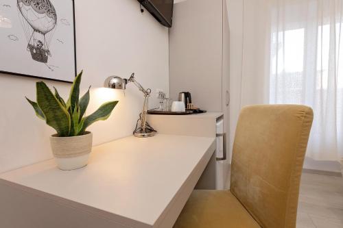 a white desk with a plant and a chair at San Martino Rooms in Pula