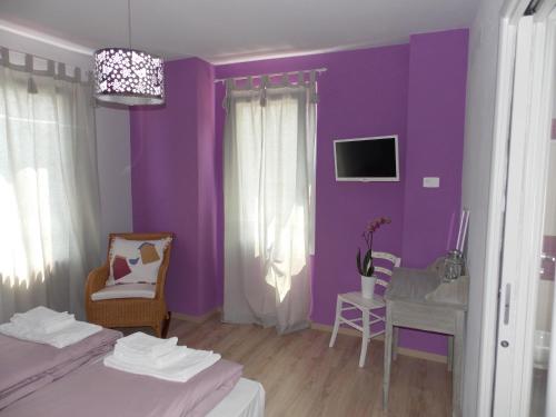 サロにあるAppartamenti Il Vecchio Mulinoの紫の壁のベッドルーム(テーブル、椅子付)
