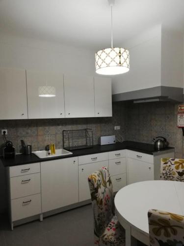 a kitchen with white cabinets and a white table at BED&SHOWER Moscavide -Self Check-In in Lisbon