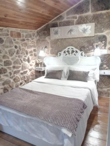 a bedroom with a white bed in a stone wall at A Casiña Vella in Poio