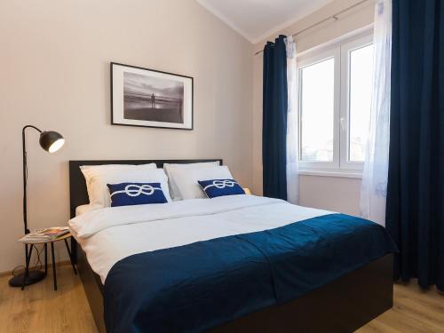 a bedroom with a bed with blue curtains and a window at New City Center Design Apartment in Poreč