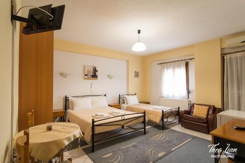 a room with two beds and a couch and a tv at Orama Rooms in Ioannina