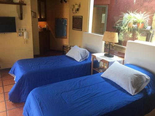 two beds in a hotel room with blue sheets at Bungalow in Our Garden in Montevideo