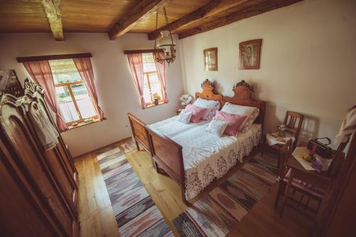 a bedroom with a bed and two windows at Country House Tunjina kuca Stara Kapela in Pavlovci