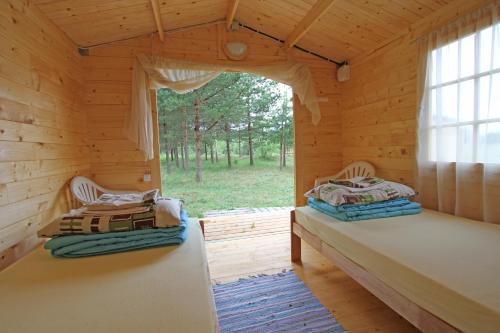 two beds in a log cabin with a window at Camping Zvejnieksēta in Pāvilosta