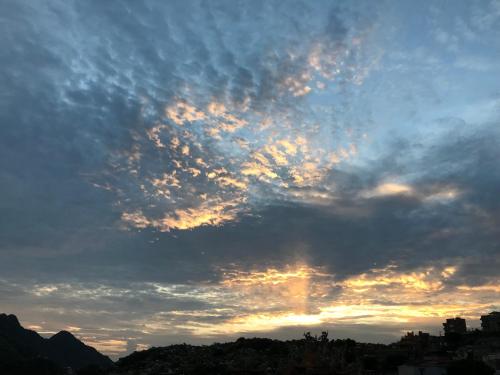 a cloudy sky with the sun setting in the background at A-HOME in Jiufen