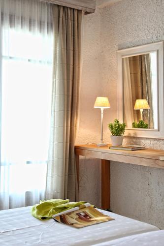 a bedroom with a bed with a table and a mirror at Skopelos Village Hotel in Skopelos Town