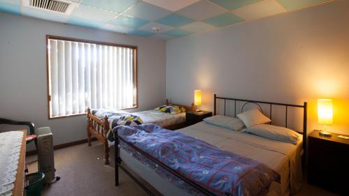 um quarto com uma cama e uma janela e uma cama sidx sidx em Kathys Place Bed and Breakfast em Alice Springs