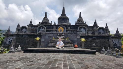 a man sitting in front of a building at Cantik Villa in Lovina