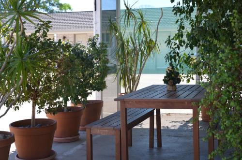 a wooden table and bench in a room with potted plants at Alexander Motor Inn in Moree